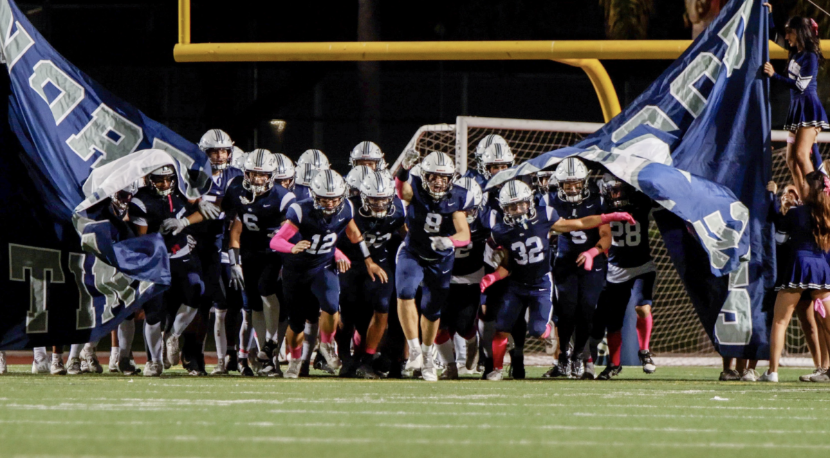 UNDER THE FRIDAY NIGHT LIGHTS: The Northwood football team runs out through the banner for their final league home game against Fountain Valley High School.